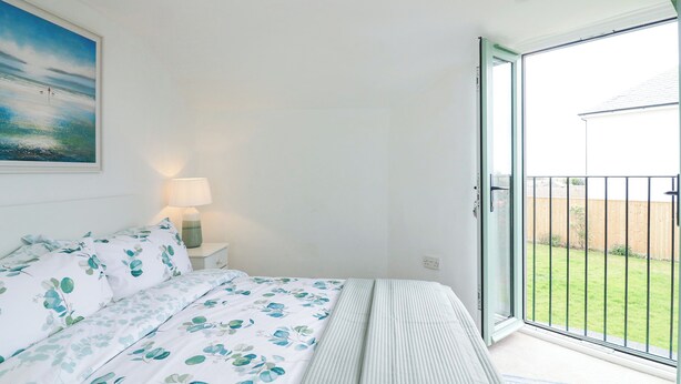 Une chambre à coucher avec un lit, une table de chevet, une lampe, une fenêtre et une vue sur un jardin.