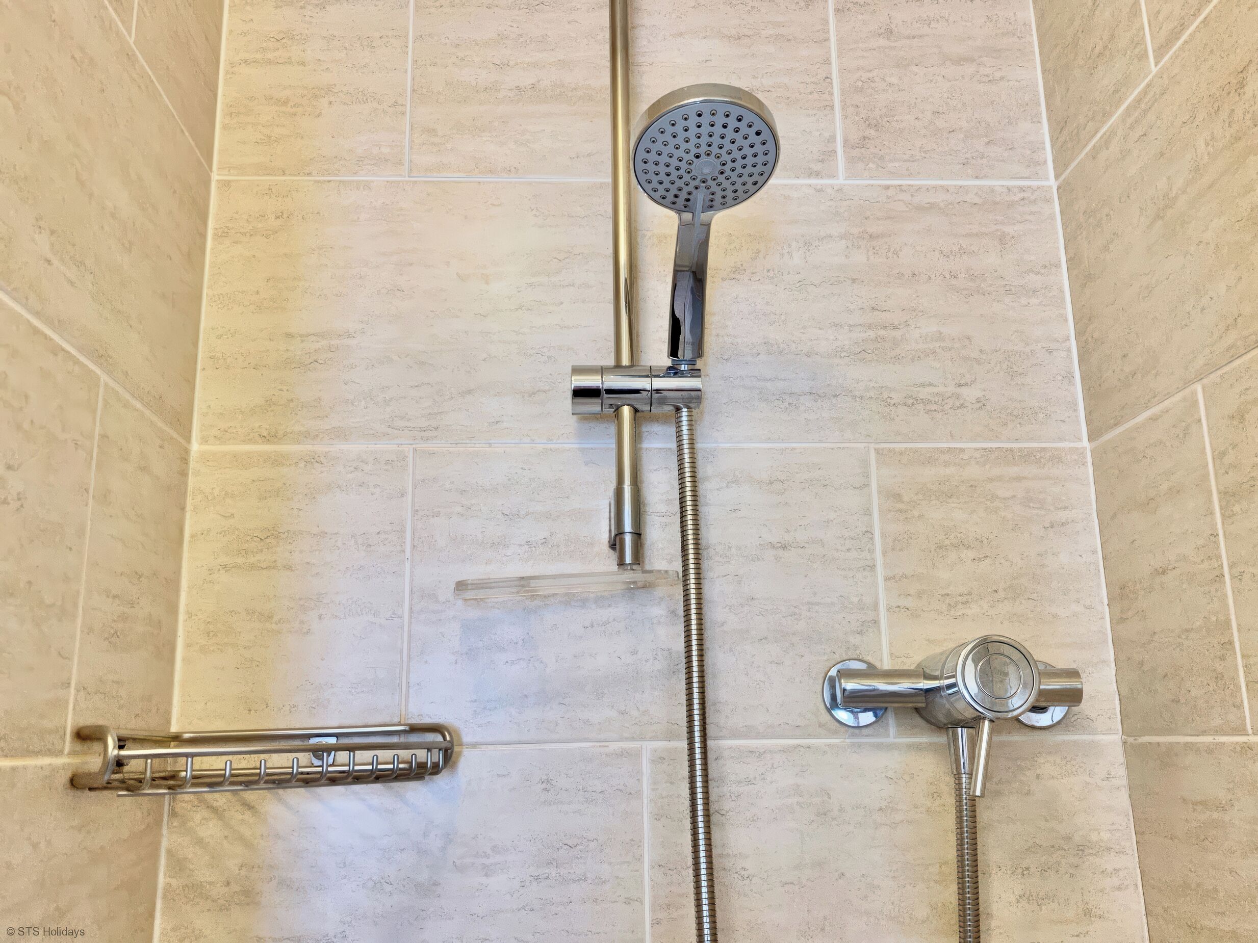 Une douche avec un pommeau de douche à main, un pommeau de douche à main doté d’un flexible et un pommeau de douche fixé au mur.