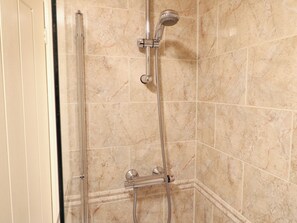 A shower with a handheld showerhead and a fixed wall-mounted showerhead, both with hoses.