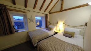 Een kamer met twee bedden, een ster decoratie, een raam met gordijnen en een lamp.