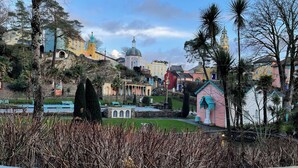 A colorful building with a dome, a bell tower, and a small pink chapel.