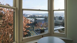 A room with a large window overlooking a harbor with boats and buildings.