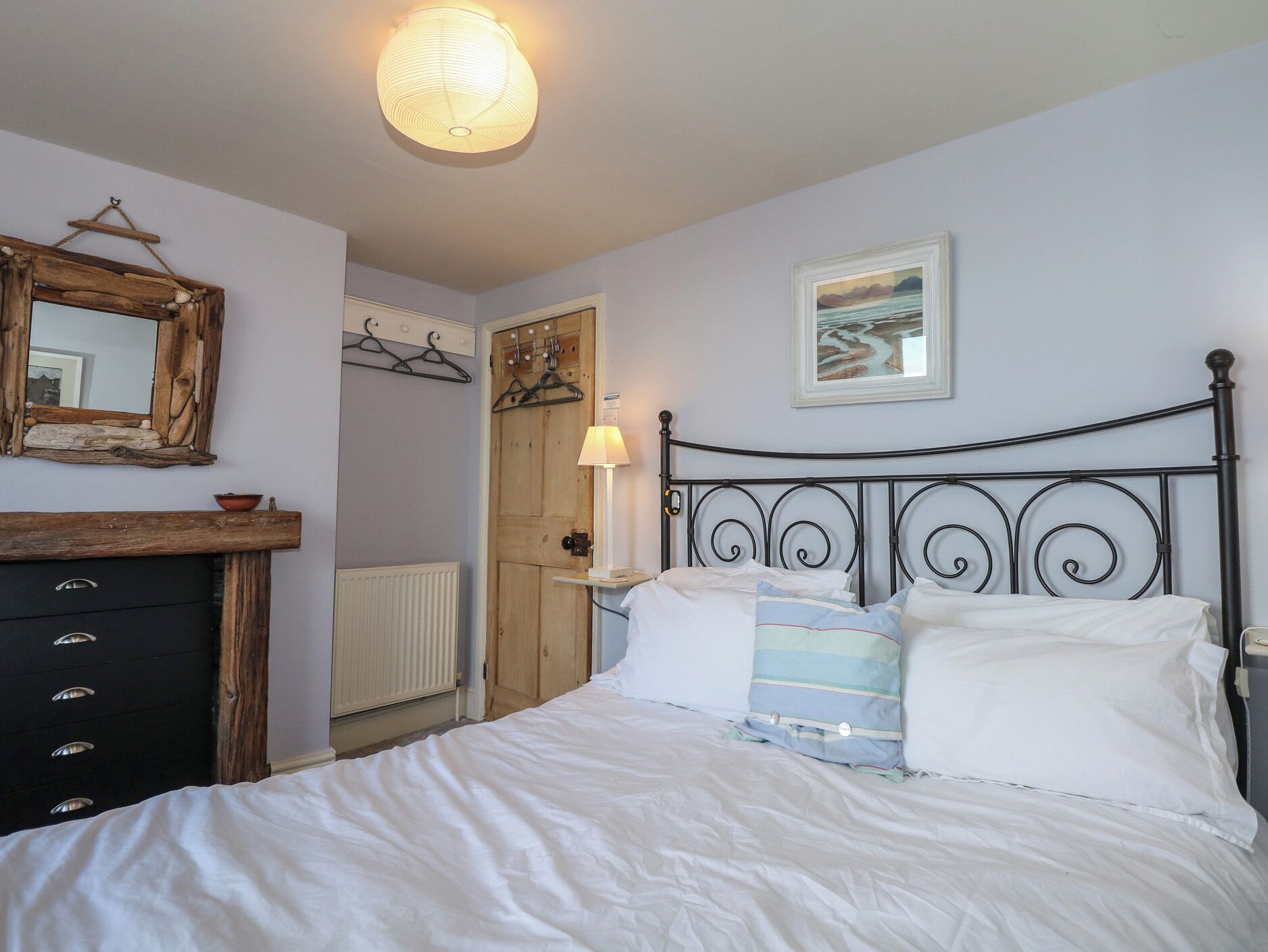 Een slaapkamer met een bed, een kaptafel, een spiegel en kunst aan de muur.