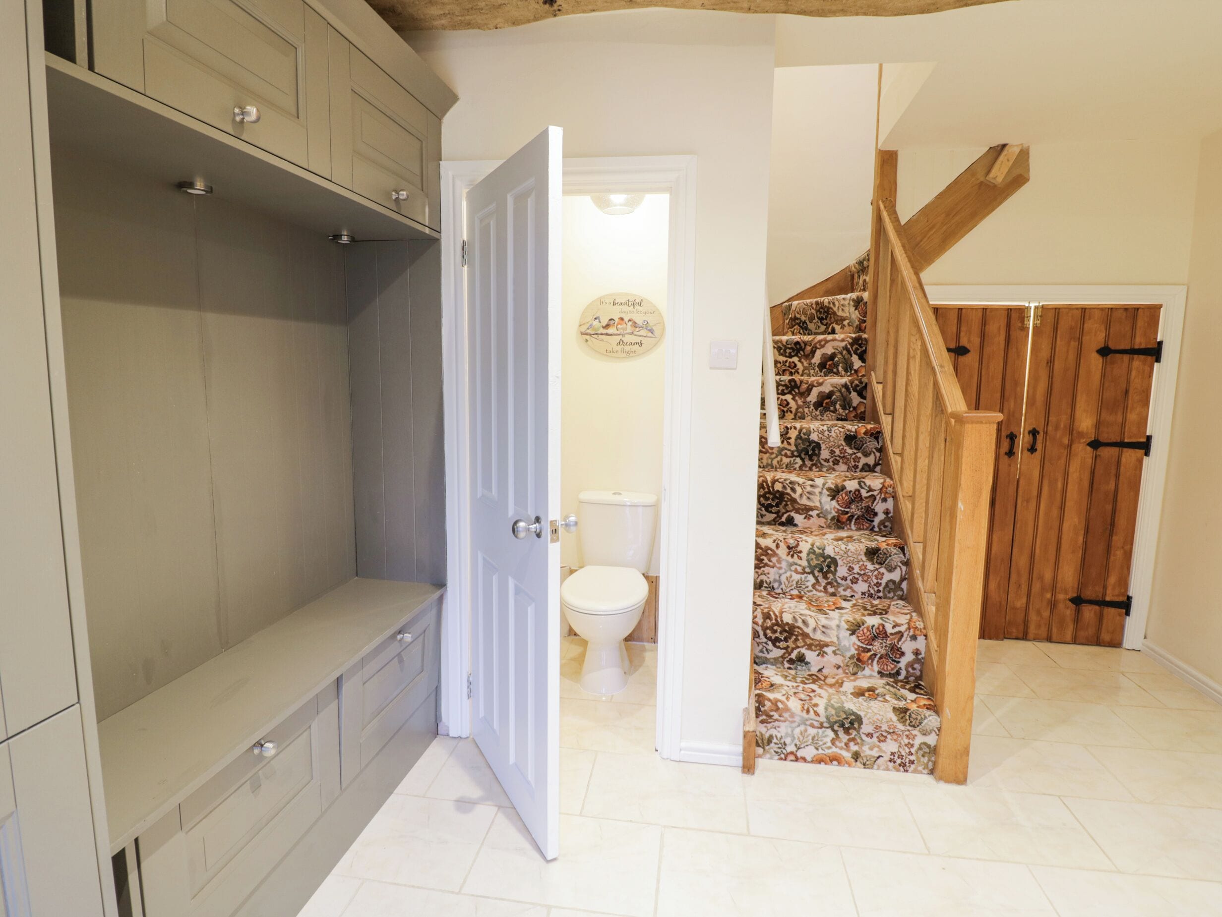 A bathroom with a toilet, a shower, and a wooden staircase.