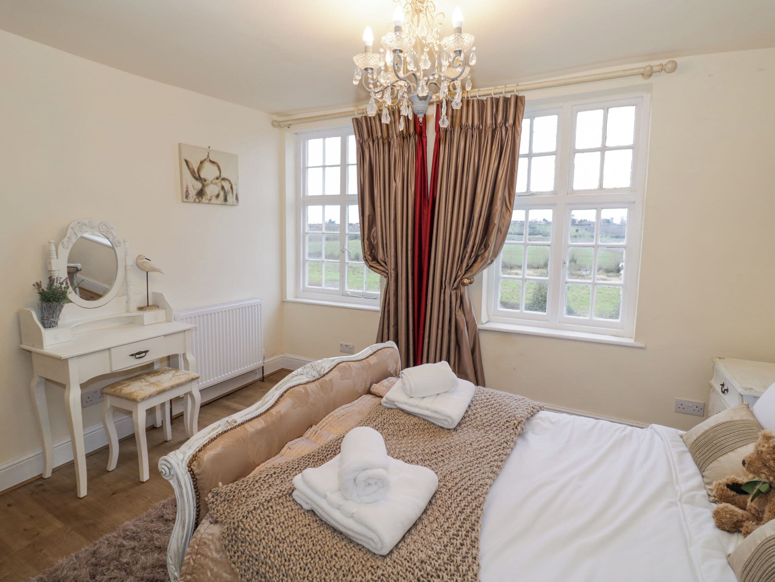 A bedroom with a bed, a dresser, a mirror, and a window with curtains.
