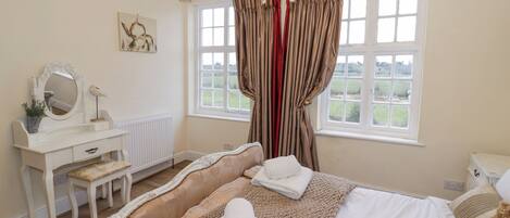A bedroom with a bed, a dresser, a mirror, and a window with curtains.