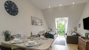 A modern living space with a dining area, kitchen, and seating area. - Sandy Bay Retreat (Tyn-y-Gongl)