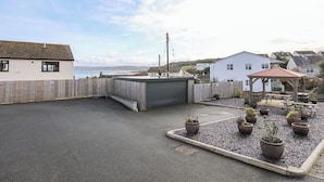A rooftop with a gravel garden, a wooden fence, and a view of the sea. - Sandy Bay Retreat (Tyn-y-Gongl)