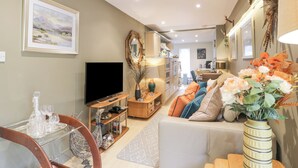 A living room with a TV, sofa, and decorative items. - Scotia At The Pow (Annan)