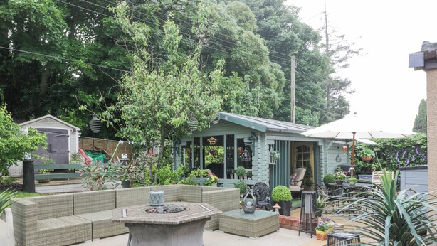 A patio area with wicker furniture, a stone table, and potted plants. - Scotia At The Pow (Annan)