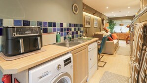 A compact kitchen with a Bosch washing machine, a coffee maker, and a sink. - Scotia At The Pow (Annan)