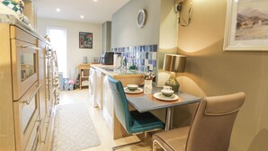 A modern kitchen with a central island, built-in appliances, and a dining area with a chair and table. - Scotia At The Pow (Annan)