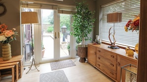 A well-lit, modern kitchen with a large window, wooden cabinets, and a dining area with a table and chairs. - Scotia At The Pow (Annan)