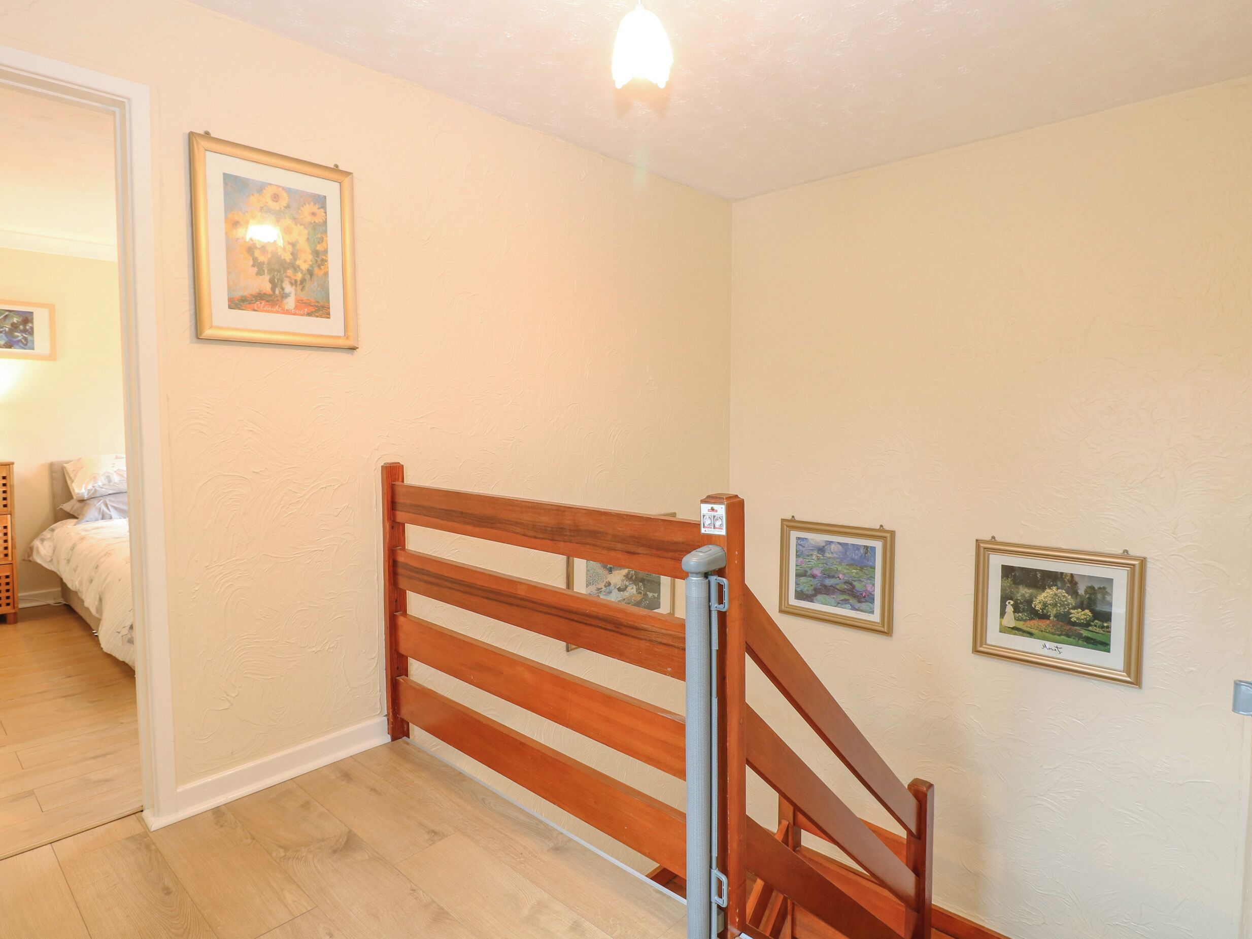 A staircase with wooden railings leading to a bedroom with a bed and a nightstand.