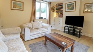A living room with a sofa, a coffee table, a television, and a bookshelf. - Tiffany's Cottage (Great Yarmouth)