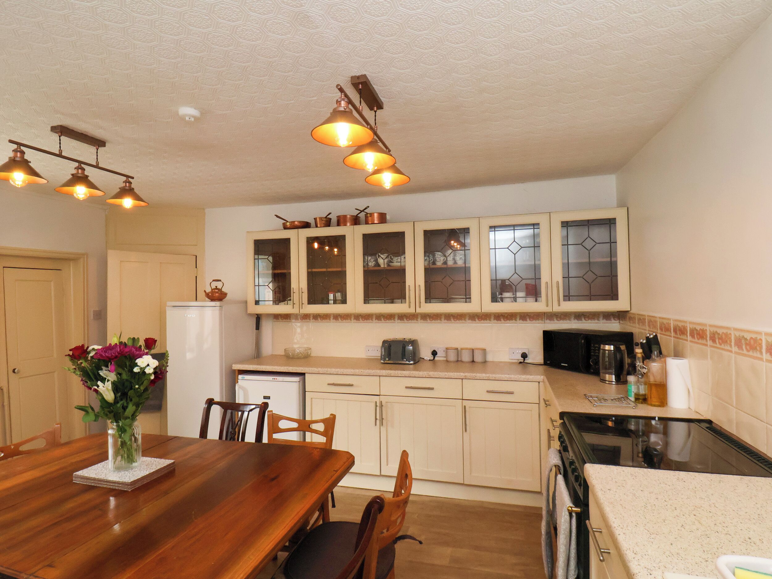 A kitchen with wooden cabinets, a dining table with chairs, and a refrigerator.