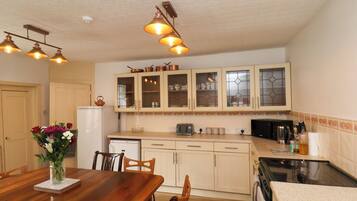 A kitchen with wooden cabinets, a dining table with chairs, and a refrigerator.
