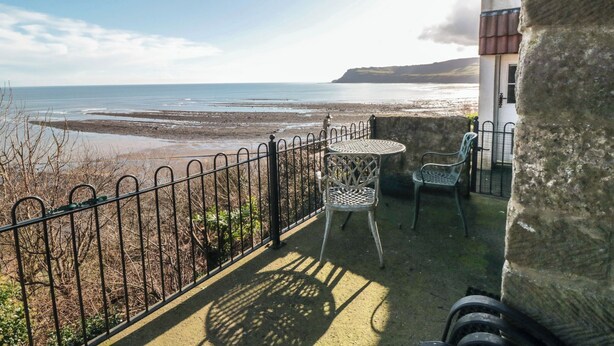 A balcony with a view of the sea, a table, two chairs, and a stone wall. - Rokeby House (Whitby)