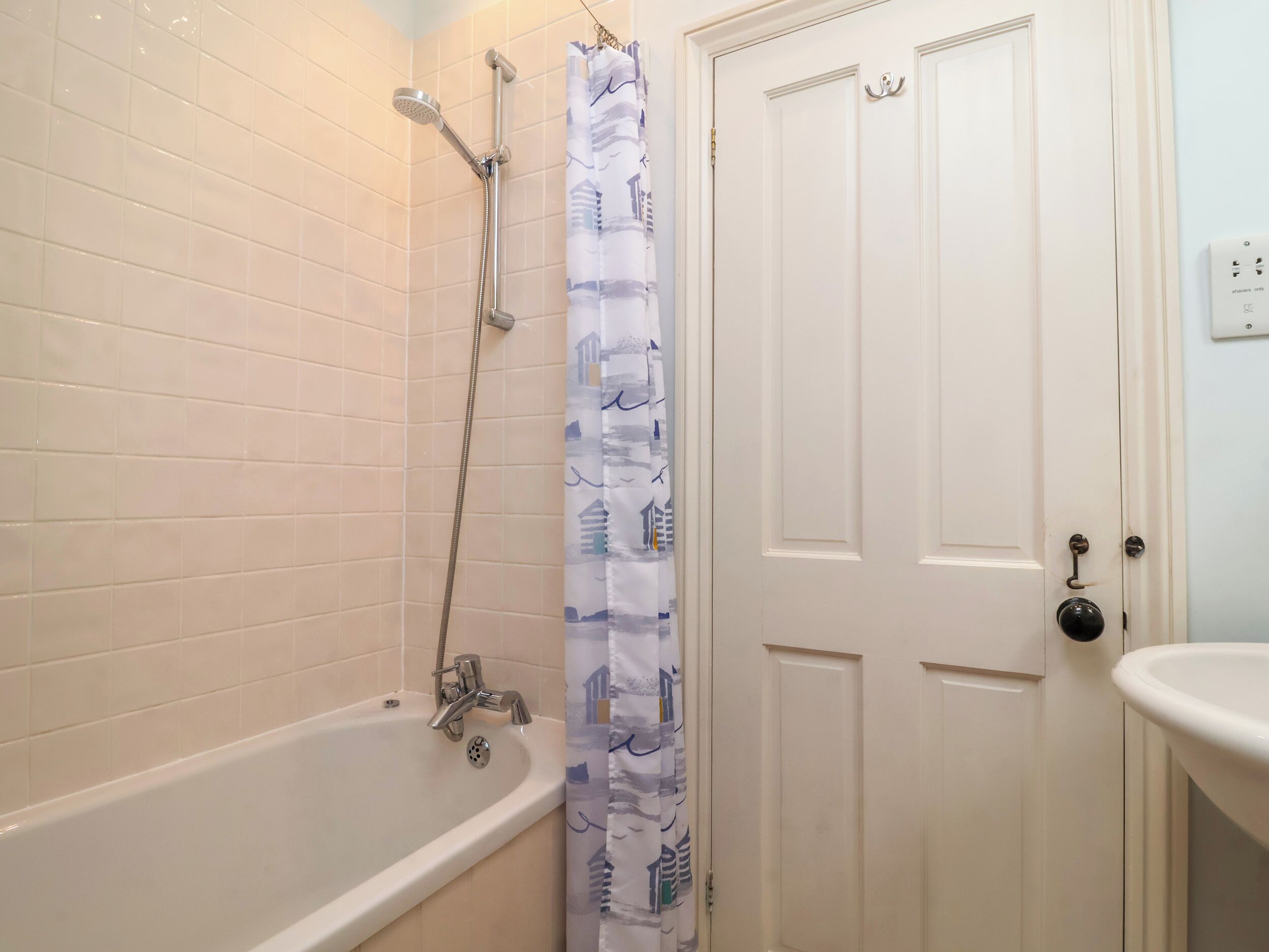 Un baño con bañera, ducha y una puerta con manija.
