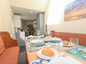 A dining area with a table set for two, featuring a bottle of wine, glasses, plates, and bread. - Home From Home (Portland)