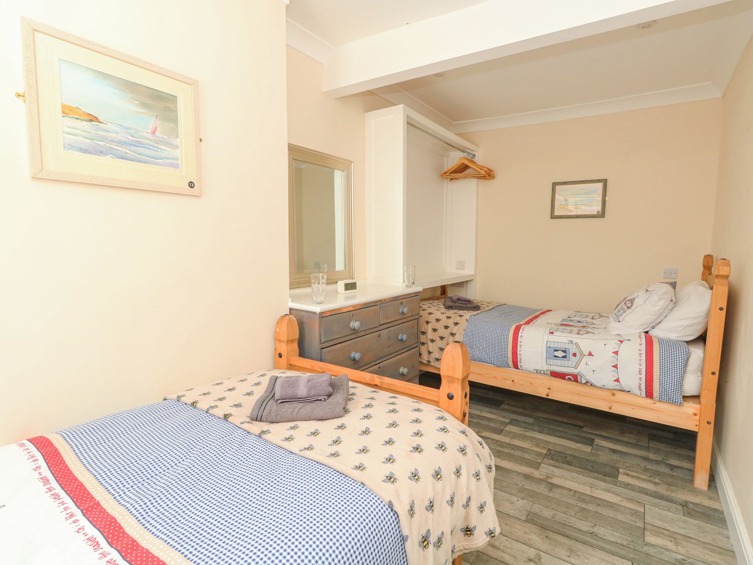 Un dormitorio con dos camas individuales, un aparador, un espejo y un cuadro en la pared.