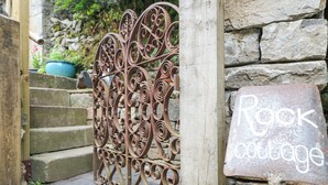 A wrought iron gate with a sign reading "Rock Cottage."