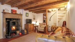 A cozy living room with a fireplace, a sofa, a television, and a staircase leading to another room.