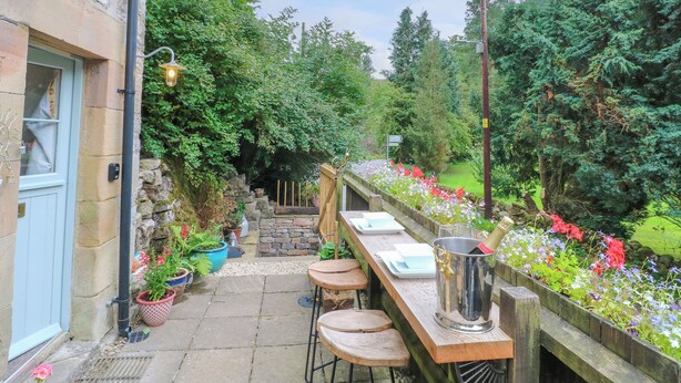 A stone building with a wooden deck, outdoor seating, and potted plants.