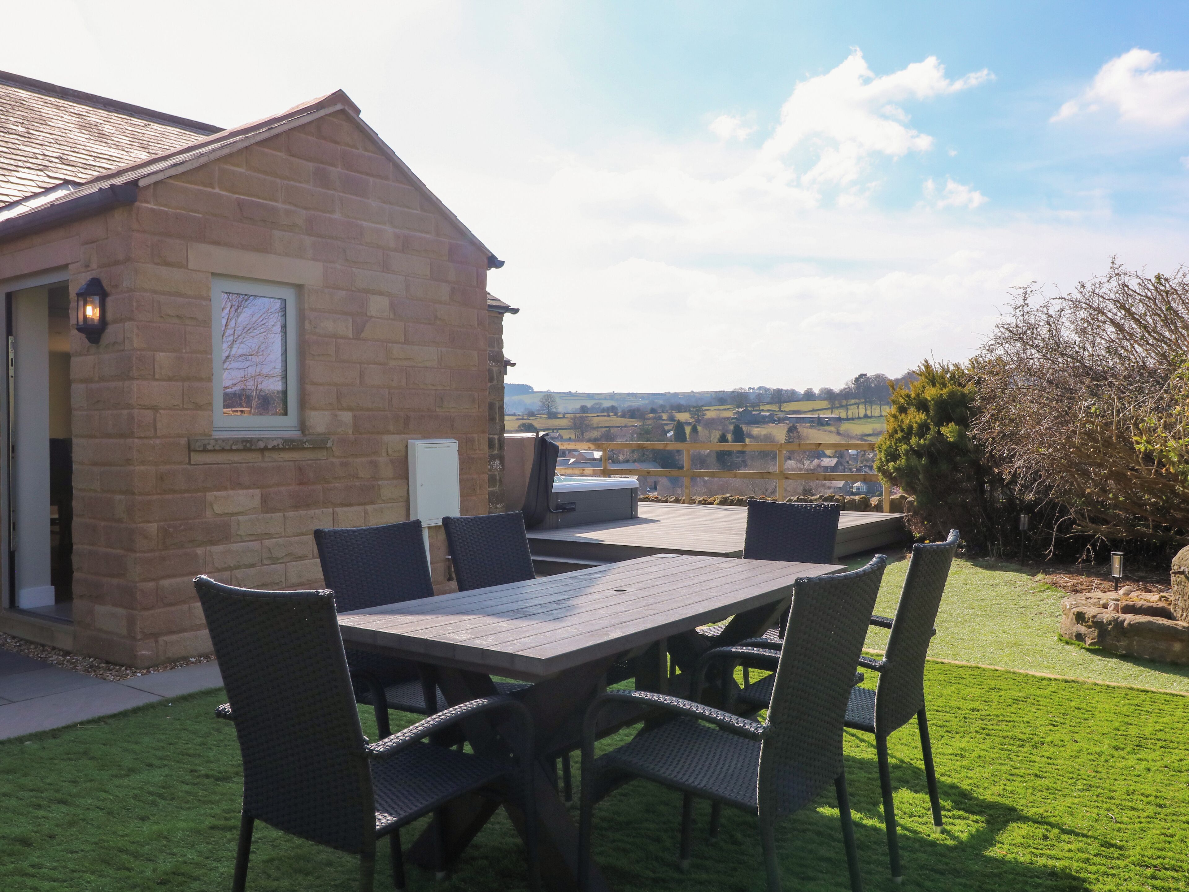 A patio with a table and chairs, a barbecue grill, and a view of the countryside.
