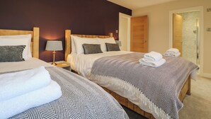 Hotellihuone, jossa on kaksi sänkyä, yöpöytä lampun kanssa ja kylpyhuone, joka näkyy avoimesta ovesta.