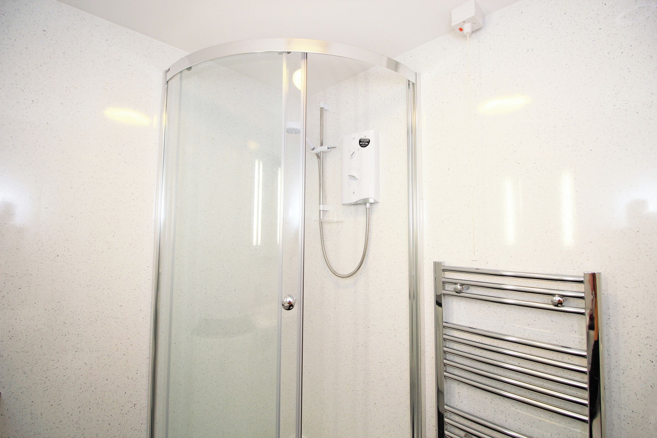 A glass-enclosed shower with a chrome towel rail.