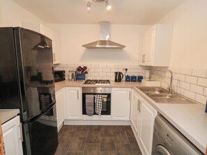 Een koelkast, een waterkoker, kookgerei, borden en bestek