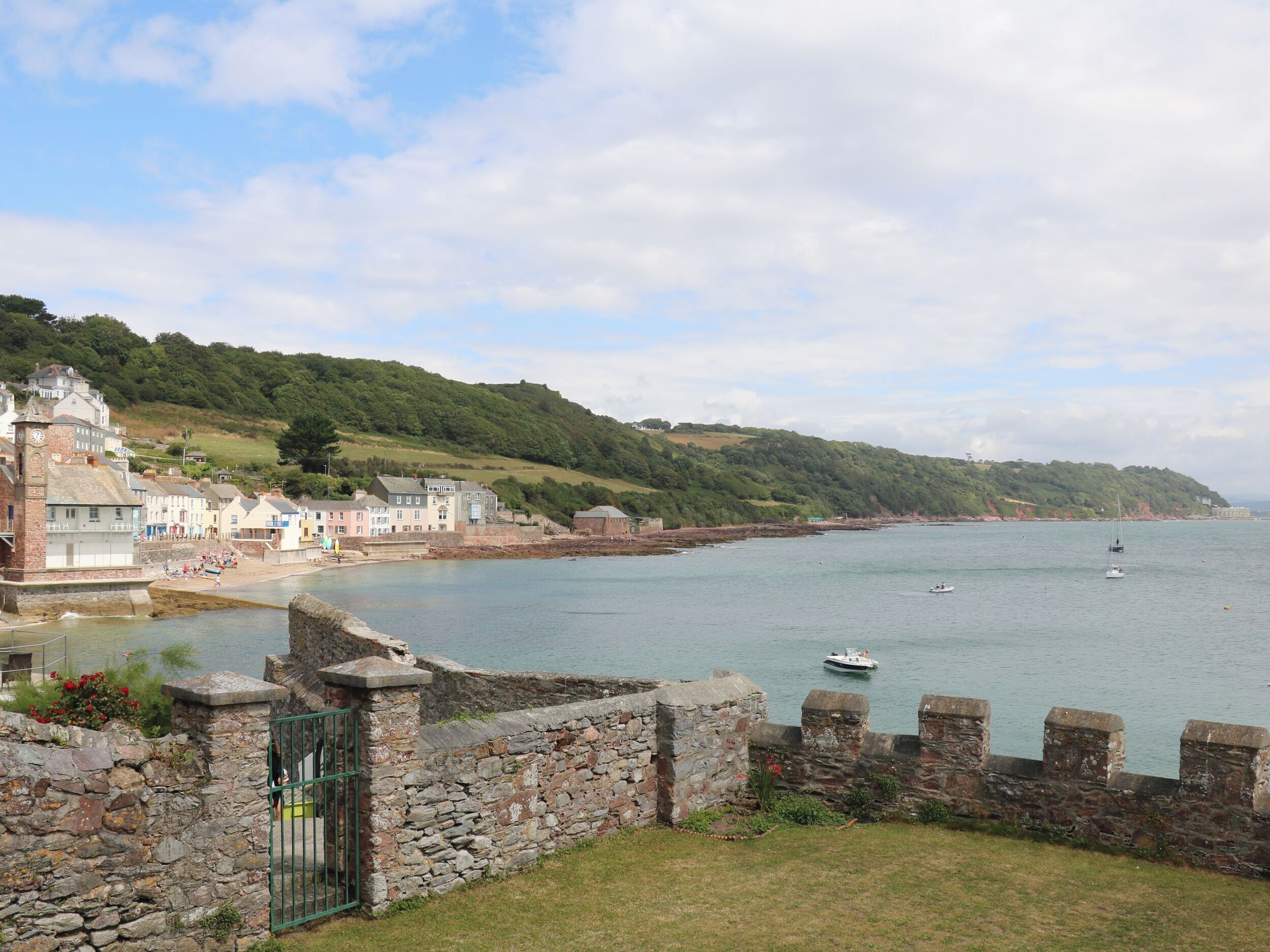 A coastal town with stone walls, a beach, and boats on the water.