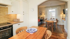 A kitchen with white cabinets, a brick backsplash, and a wooden dining table with chairs. - Springfield (Torpoint)