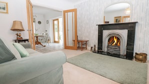 A living room with a sofa, a fireplace, a dining area with chairs, and a table. - Kerangarth (Corbridge)