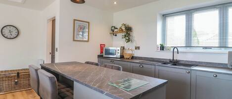 A modern kitchen with a central island, grey cabinets, a microwave, and a sink.