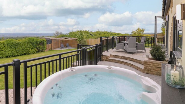 Ein Whirlpool auf einer Terrasse mit Blick ins Grüne.