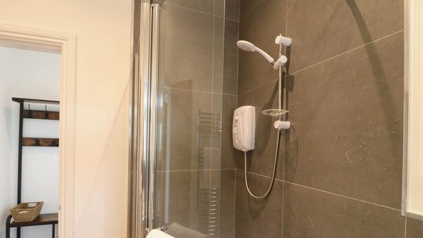 A glass-enclosed shower area with a handheld showerhead and a handheld shower attachment. - Highview Stables (Chesterfield)