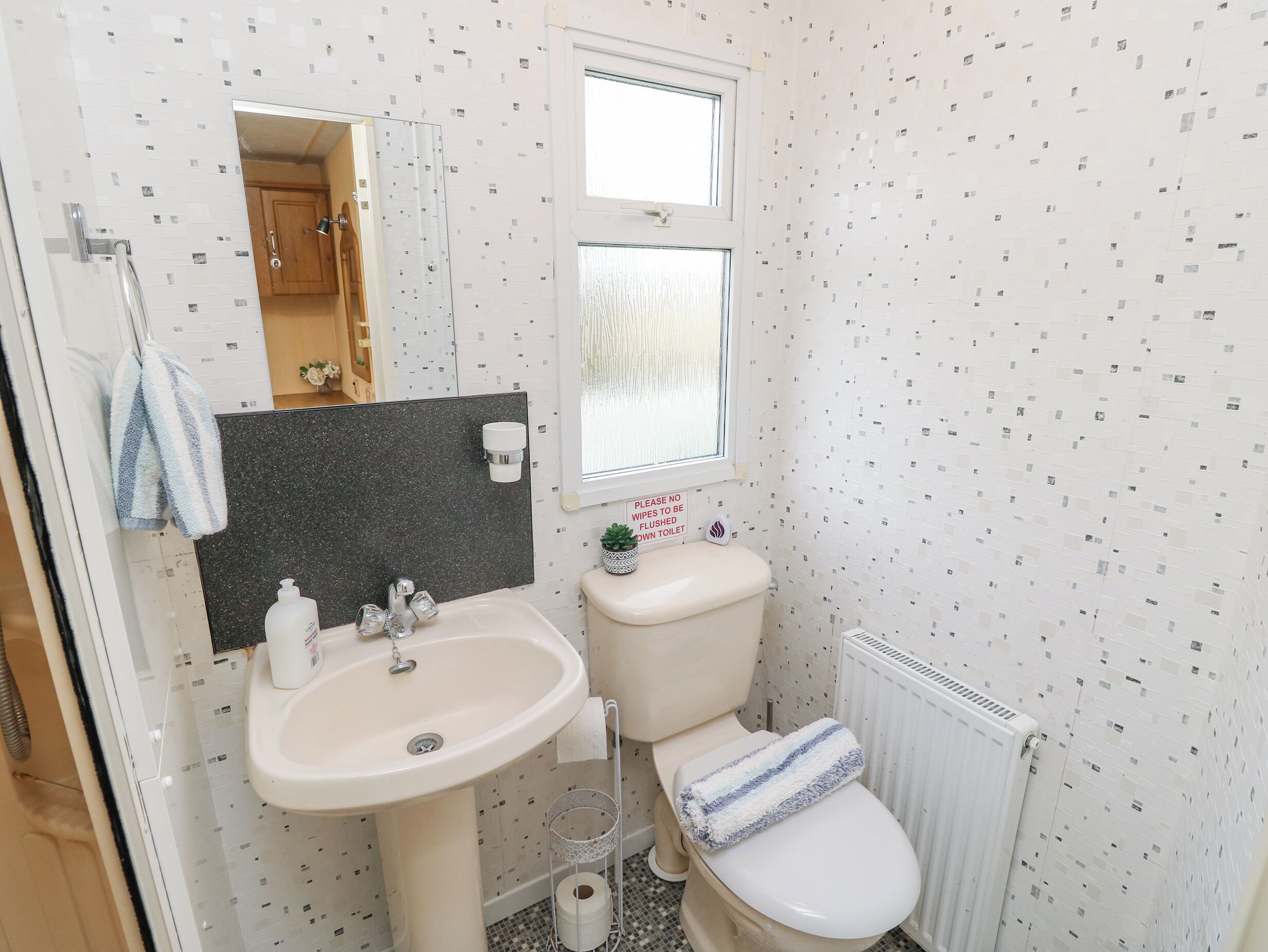 Une salle de bain avec un lavabo, un miroir, des toilettes et une fenêtre.