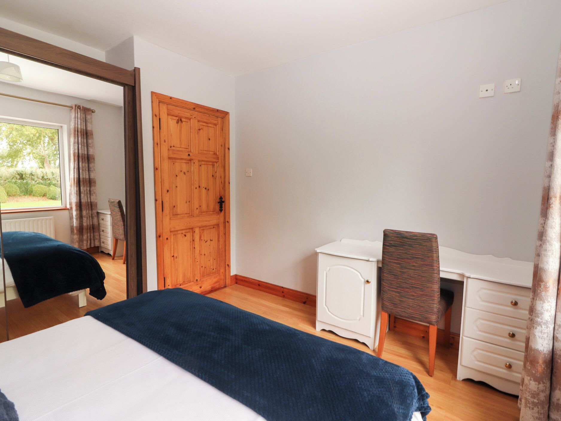 A bedroom with a bed, a desk, and a chair.