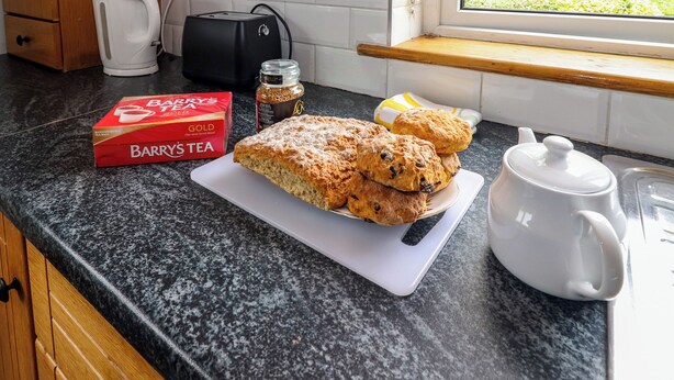 Eine Küchenarbeitsfläche mit einer Schachtel Barry’s Tea, einem Zuckerbehälter, einer weißen Teekanne und einem Brot.