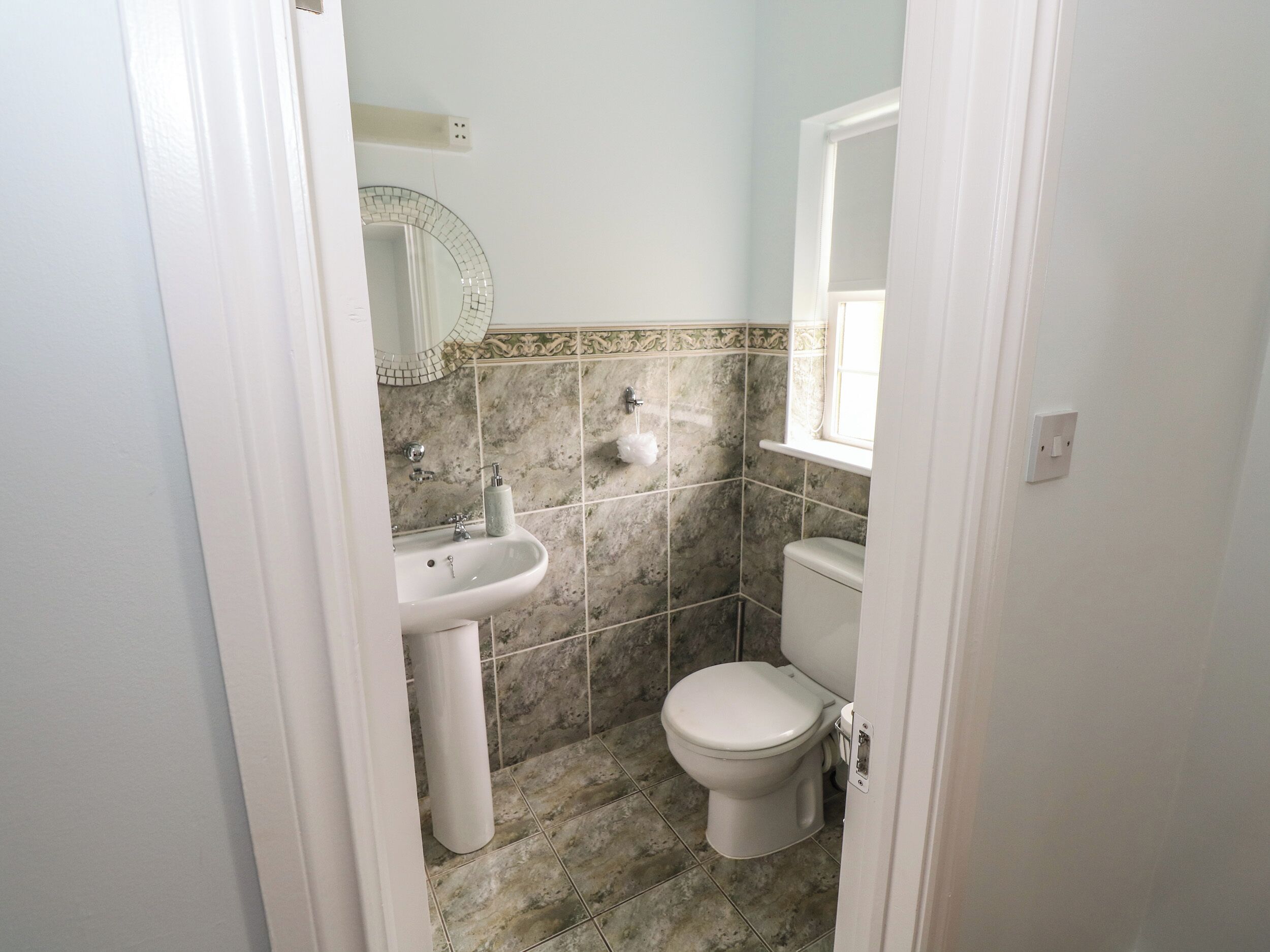 A small bathroom with a sink, toilet, and a mirror.