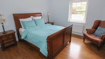 Una camera da letto con un letto in legno, due comodini, una sedia e una finestra.