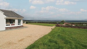 A house with a gravel driveway, a grassy lawn, and a view of the sea. - Cois Leice (Mulranny)