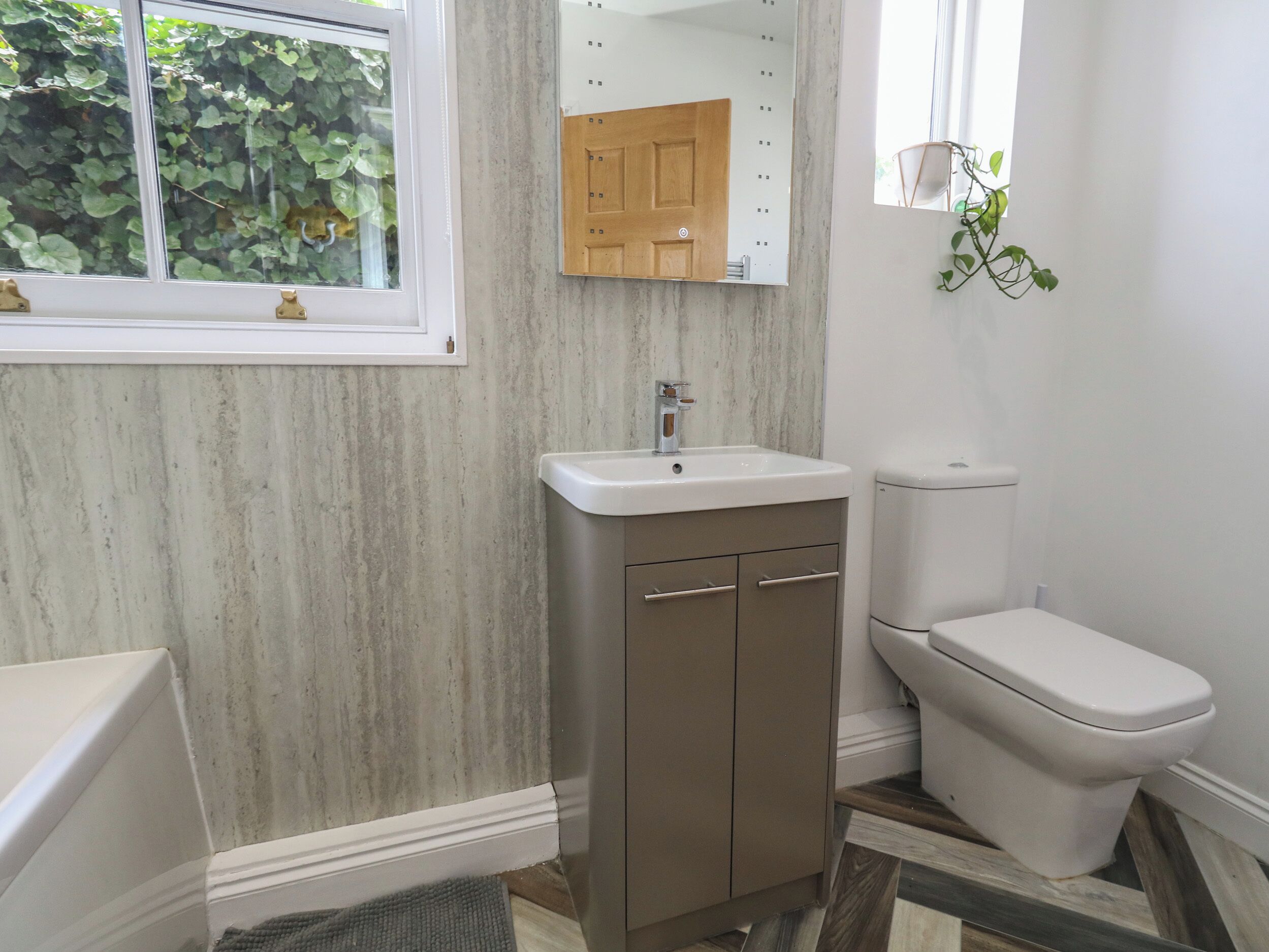 A bathroom with a wooden vanity, a white sink, and a toilet.