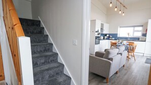 A staircase leading to a living area with a kitchen in the background. - Coastguard View (Portland)