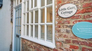 A brick building with a sign reading "Little Gem Cottage" and another sign for "Yorkshire Coastal Cottages". - Little Gem (Whitby)