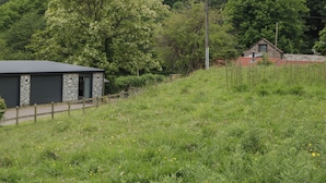 A rural property with a stone building, a wooden fence, and a red-roofed house. - The Snug (Chepstow)