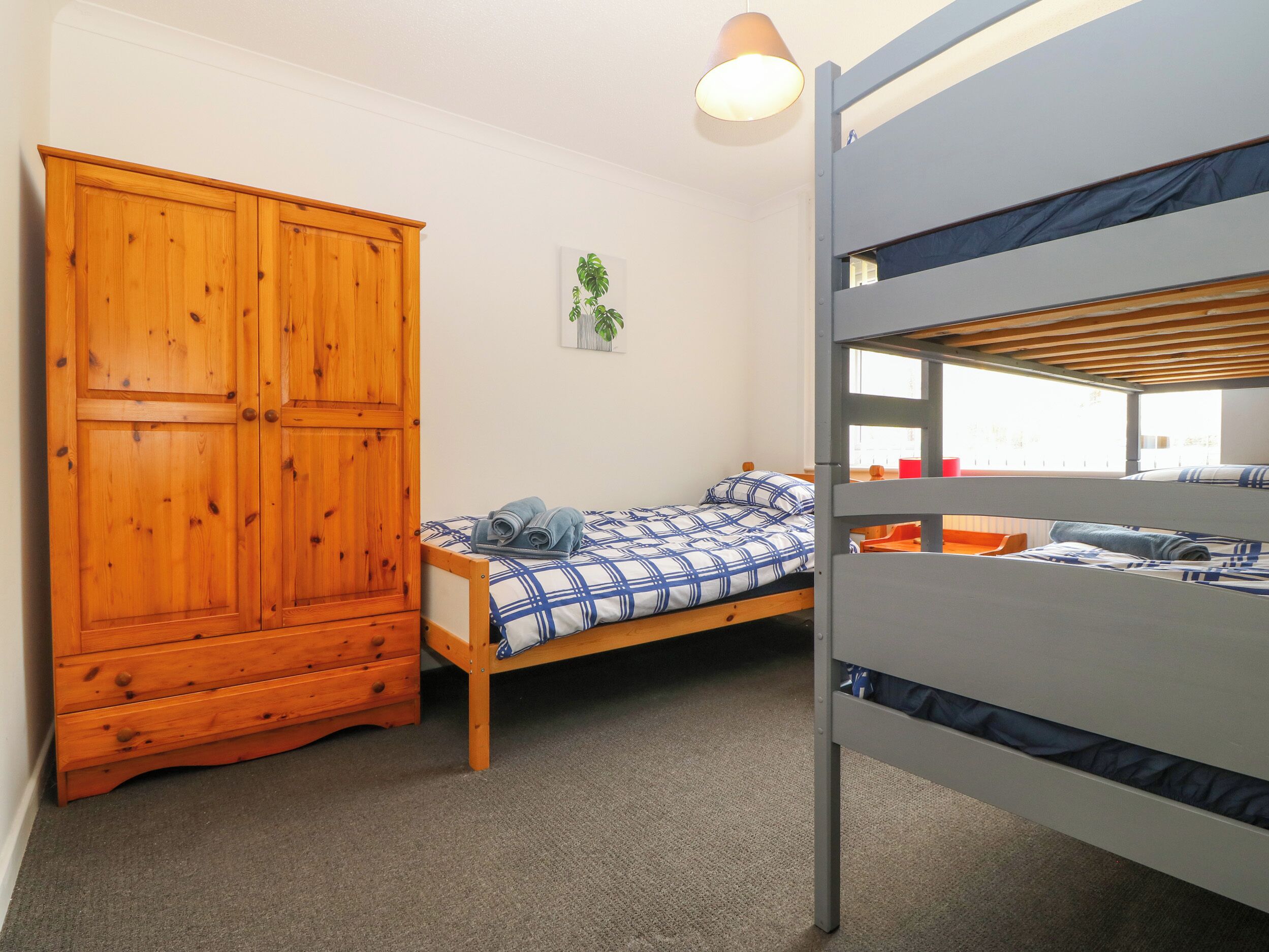 A room with a bunk bed, a wooden wardrobe, and a small bedside table.