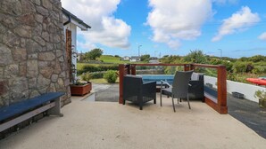 Eine Terrassensitzgruppe mit Steinmauer, Pool und Blick auf eine grüne Landschaft.
